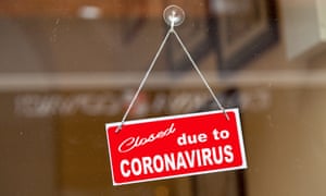 Cartel rojo colgado en la puerta de cristal de una tienda que dice 'Cerrado por coronavirus'.