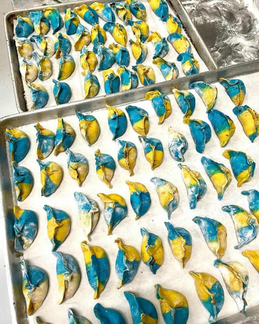 Dos sartenes contienen varias docenas de albóndigas azules y amarillas.