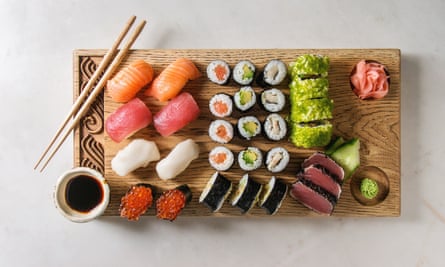 Nigiri y rollos de sushi presentados en bandeja de madera.