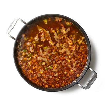 Agregue la mezcla de especias, cocine por unos minutos más, luego vierta el caldo y la salsa picante.
