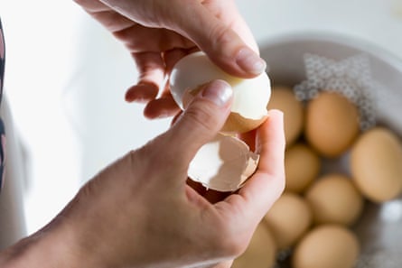 Primer plano de manos pelando un huevo cocido.