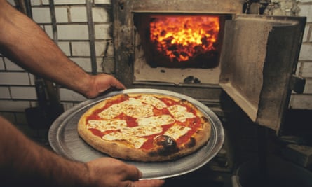 manos en la pizza al lado del horno